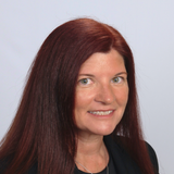 A woman with long red hair is smiling for the camera