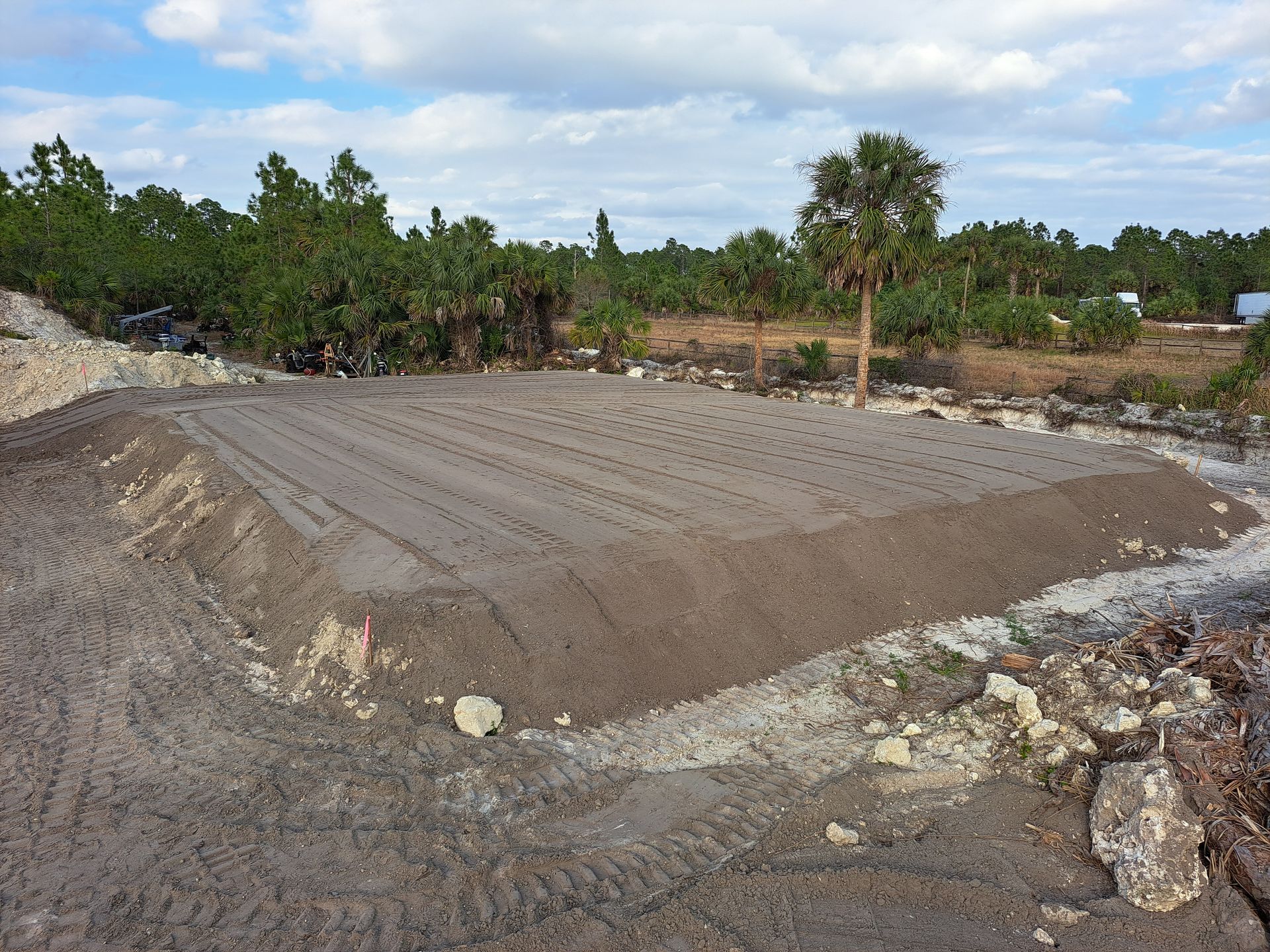 A dirt field with palm trees in the background