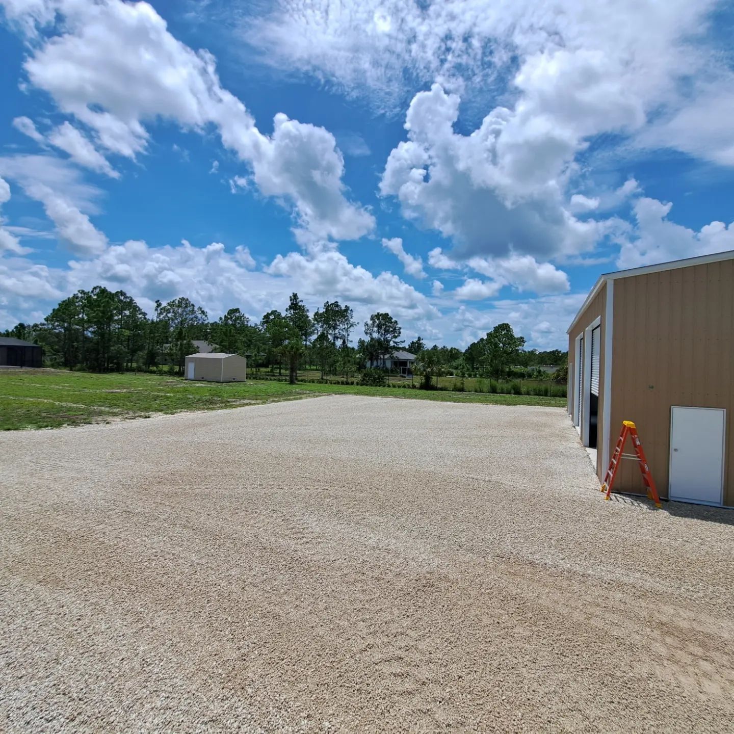 A gravel driveway with a building in the background