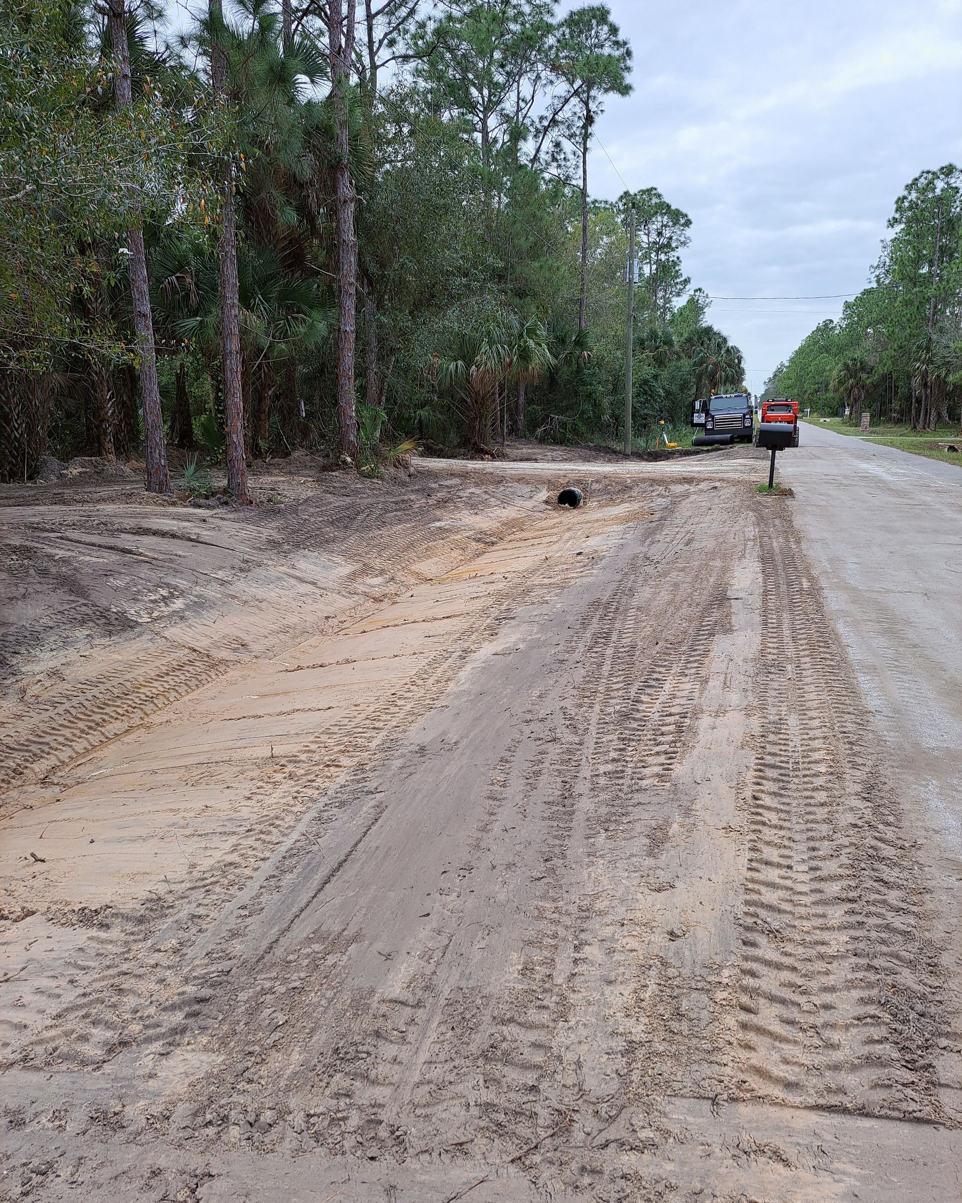 A car is parked on the side of a dirt road.