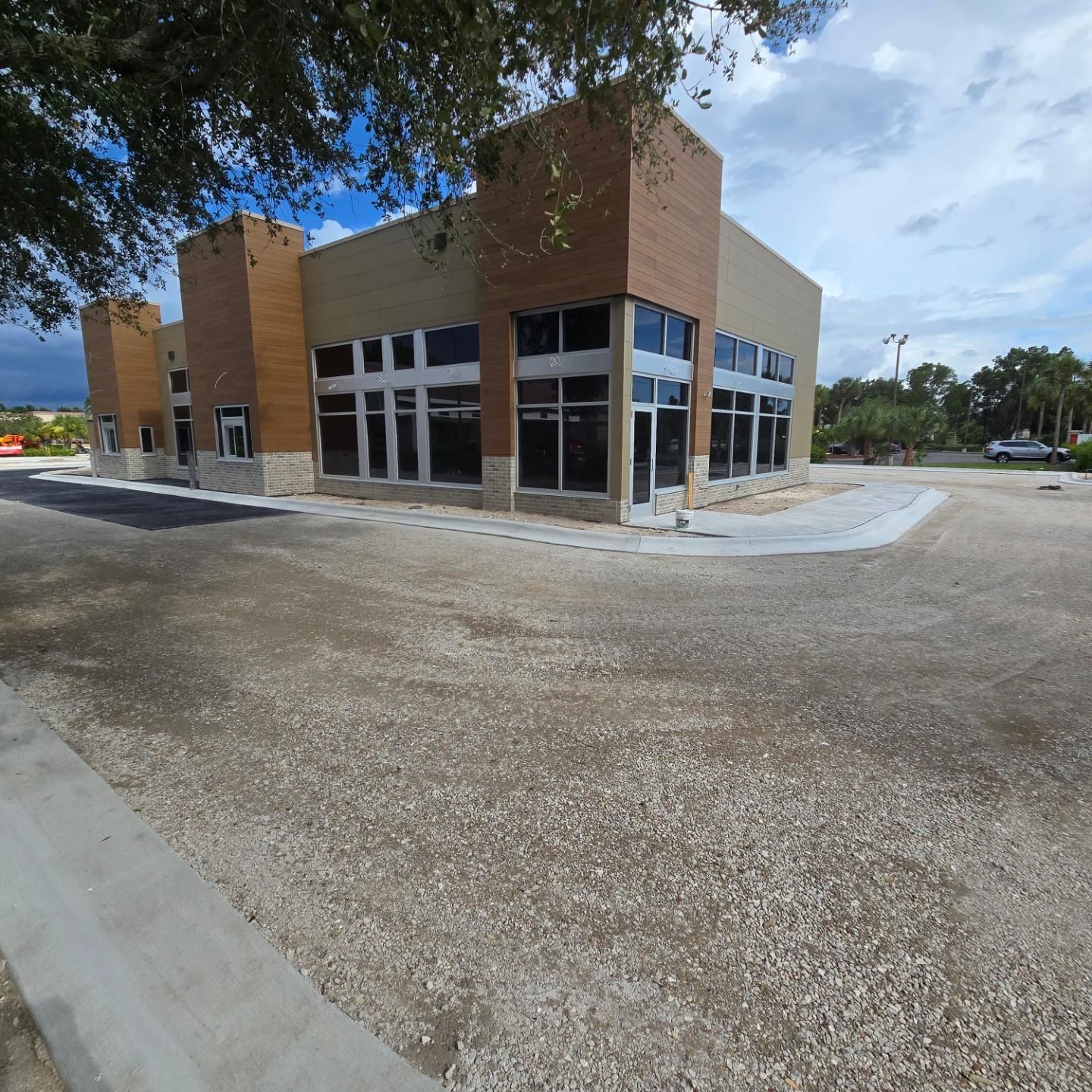 A building with a lot of windows has a gravel driveway in front of it