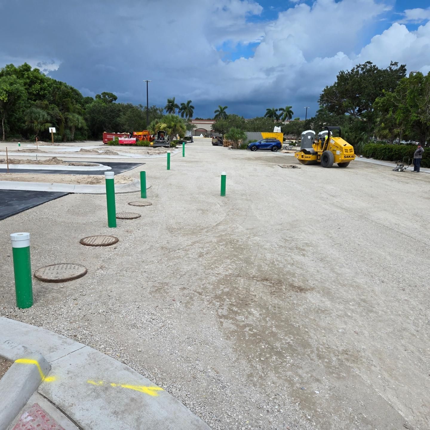 A row of green poles are lined up on the side of a dirt road