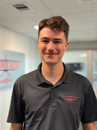 Smiling man in a dark polo shirt standing indoors in an office setting
