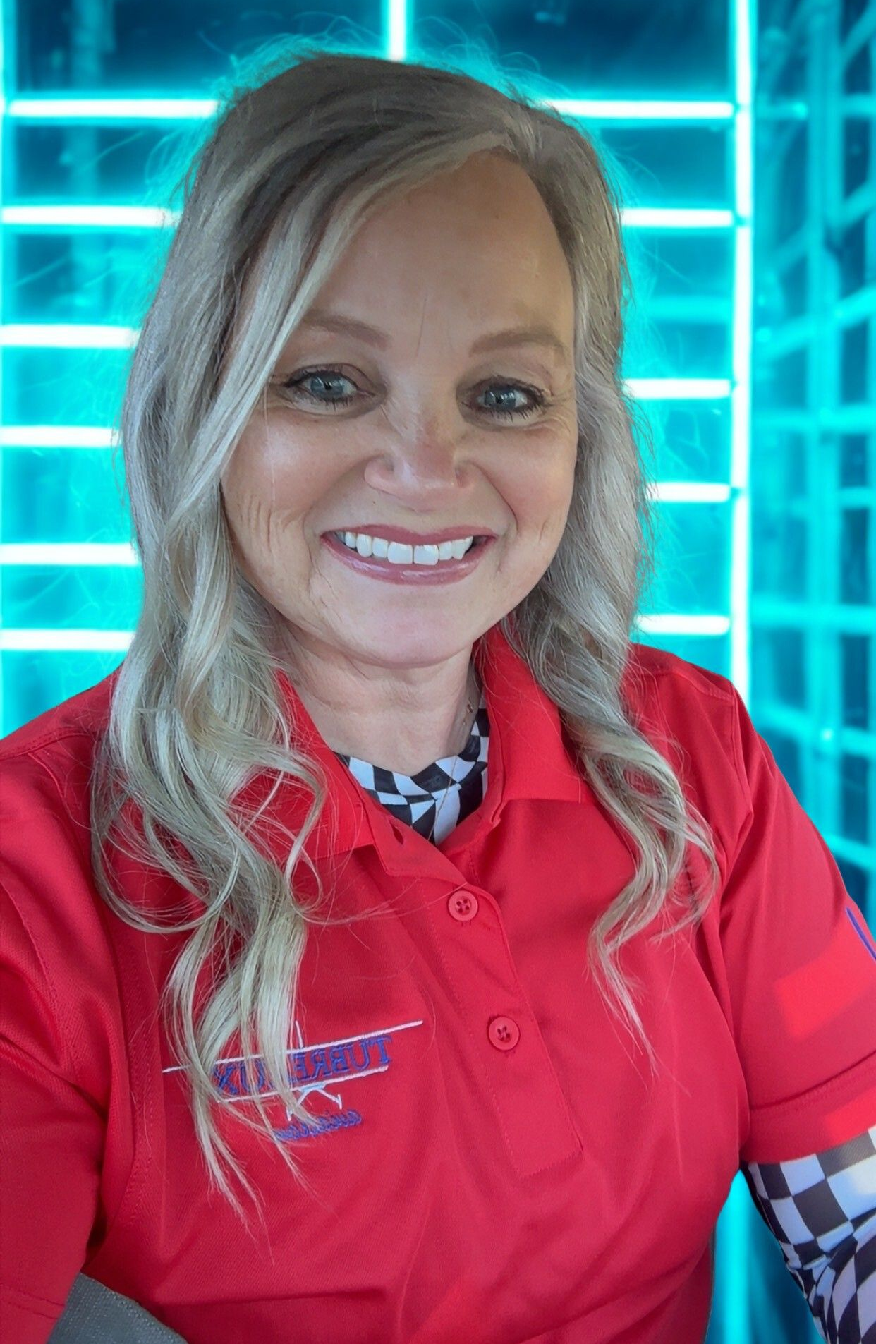 Smiling woman in a red polo shirt standing before a glowing blue grid backdrop