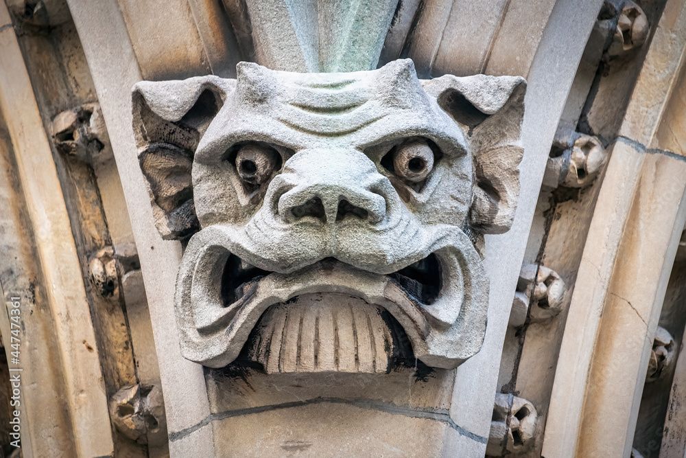 A gargoyle head is carved into the side of a building.