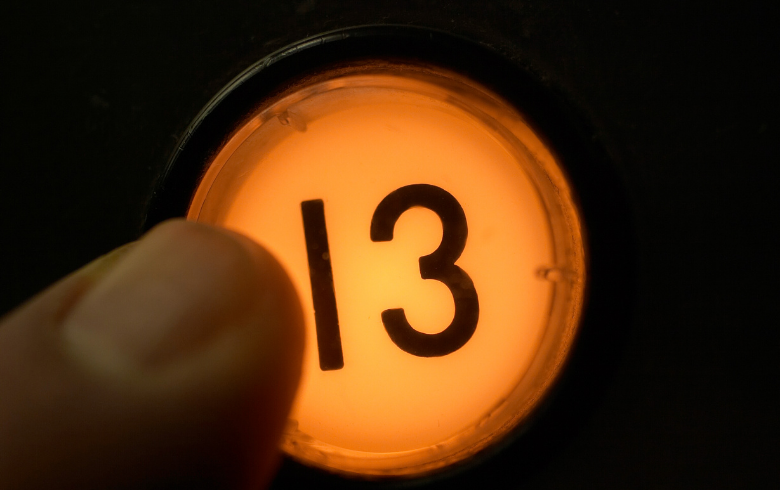 A person is pressing the number 13 button in an elevator