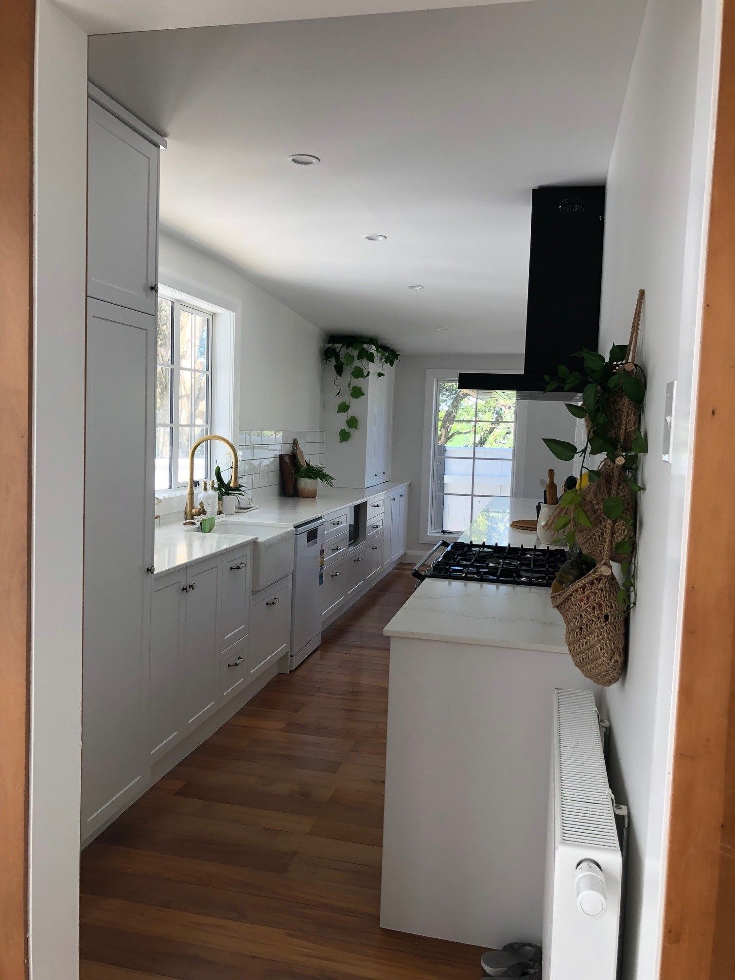 A kitchen with white cabinets and wooden floors and a stove top oven.