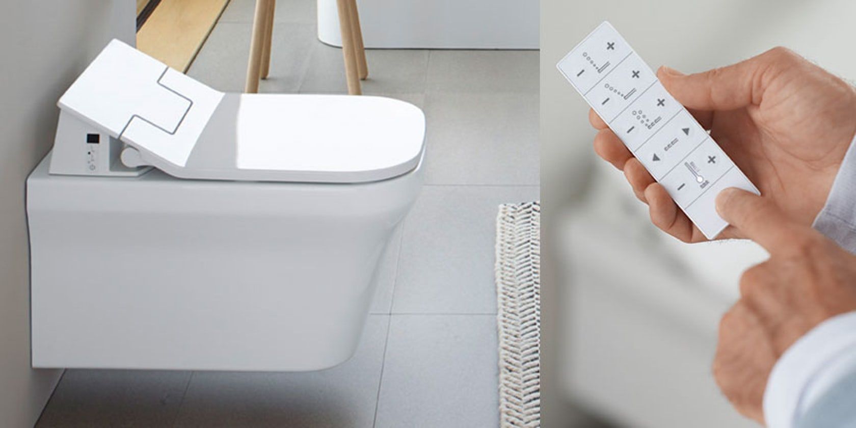 A person is holding a remote control in front of a toilet.