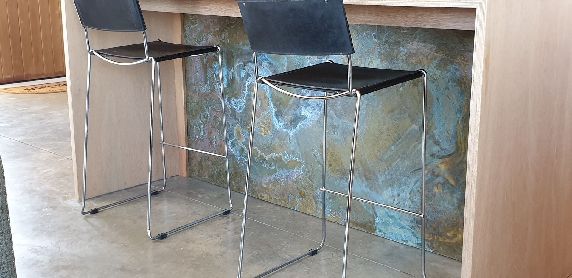 Two bar stools are sitting next to a wooden table.