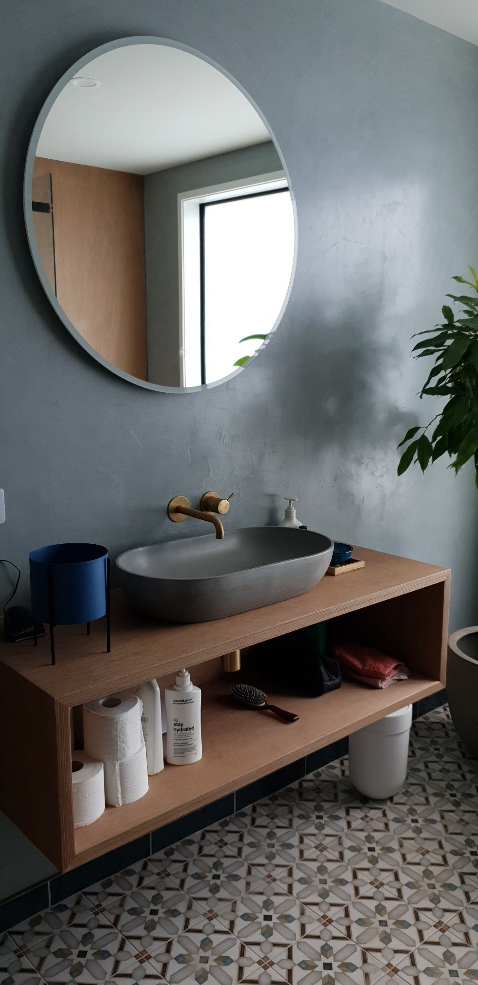 A bathroom with a sink , mirror and shelf.