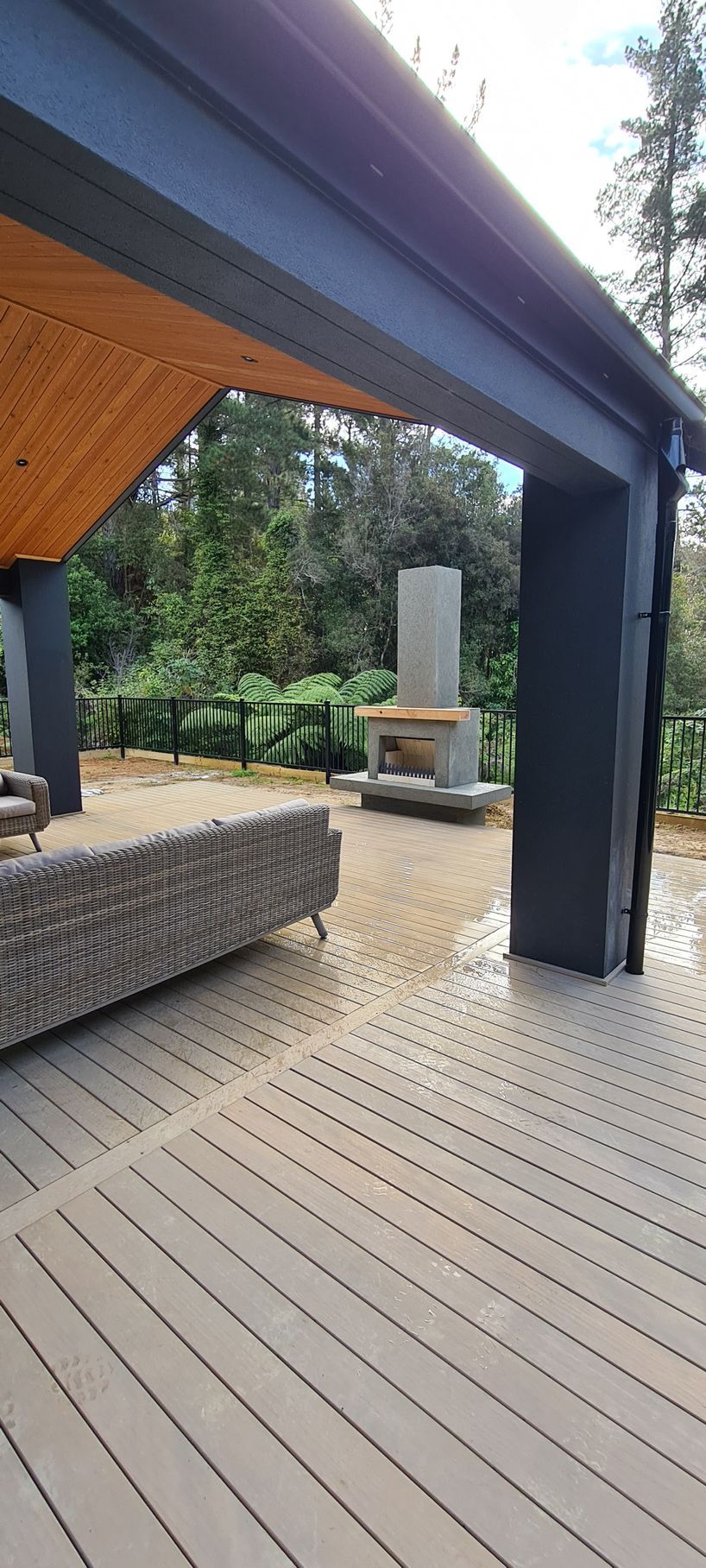 A deck with a fireplace and a couch under a canopy.
