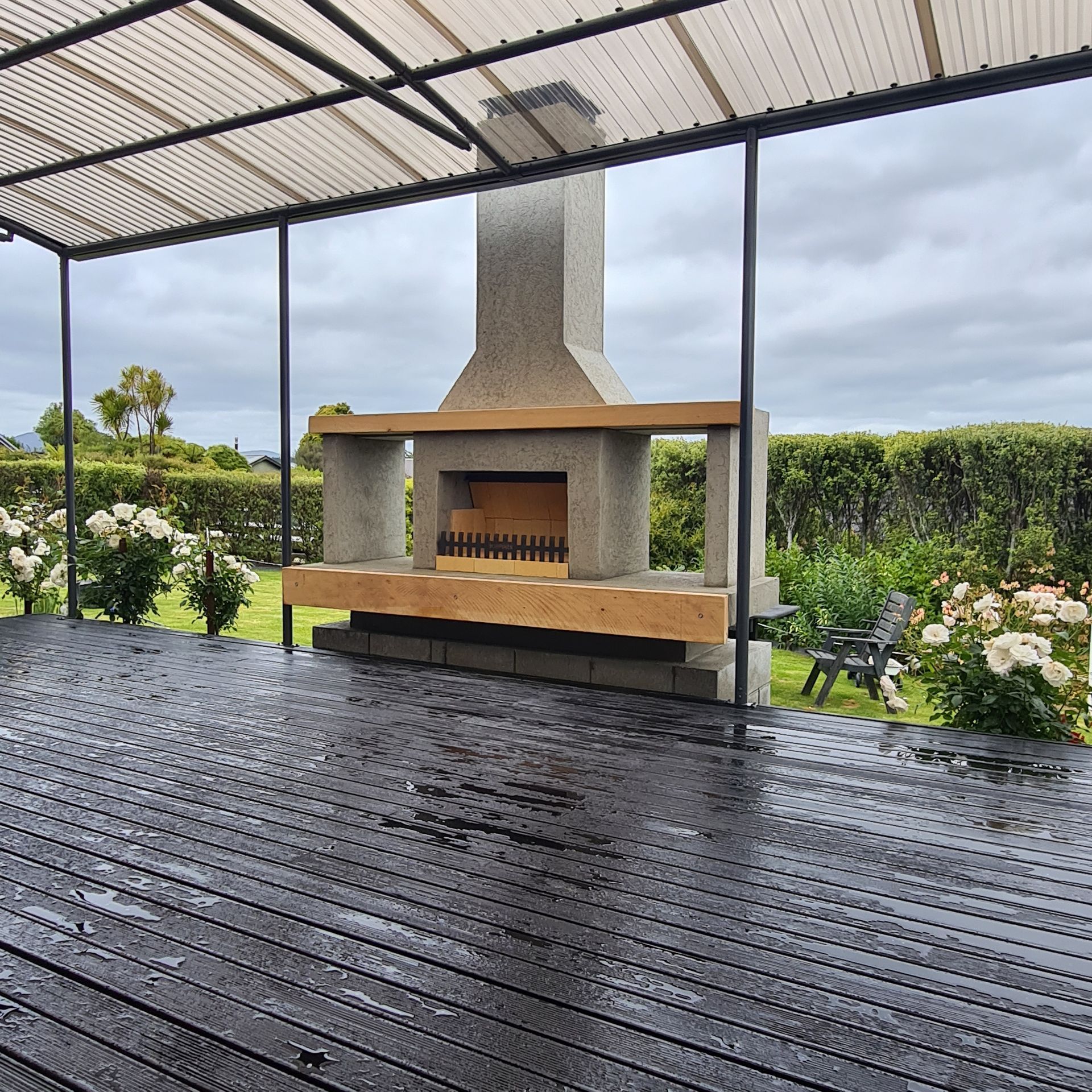 A wooden deck with a concrete fireplace in the middle