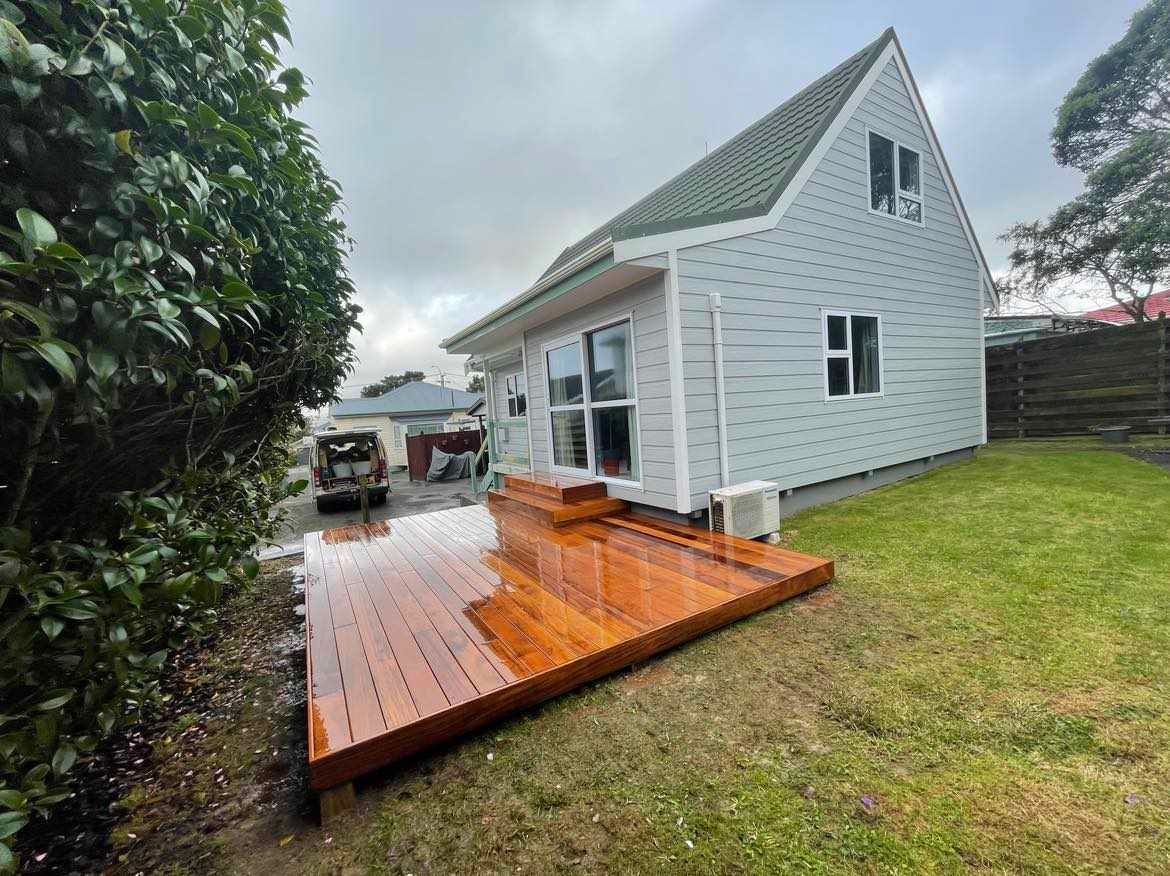 A white house with a wooden deck in front of it.