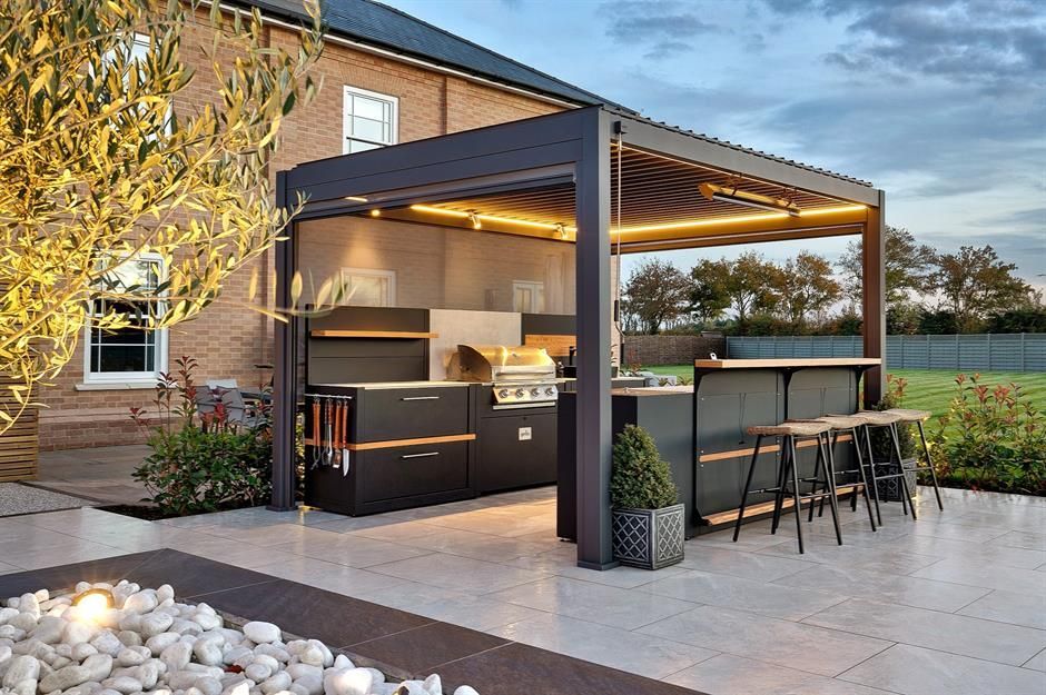 A patio with a kitchen and a bar under a pergola.
