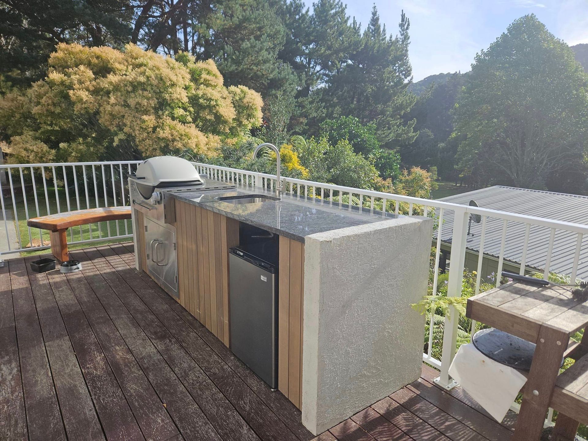 A wooden deck with a grill and a refrigerator on it.