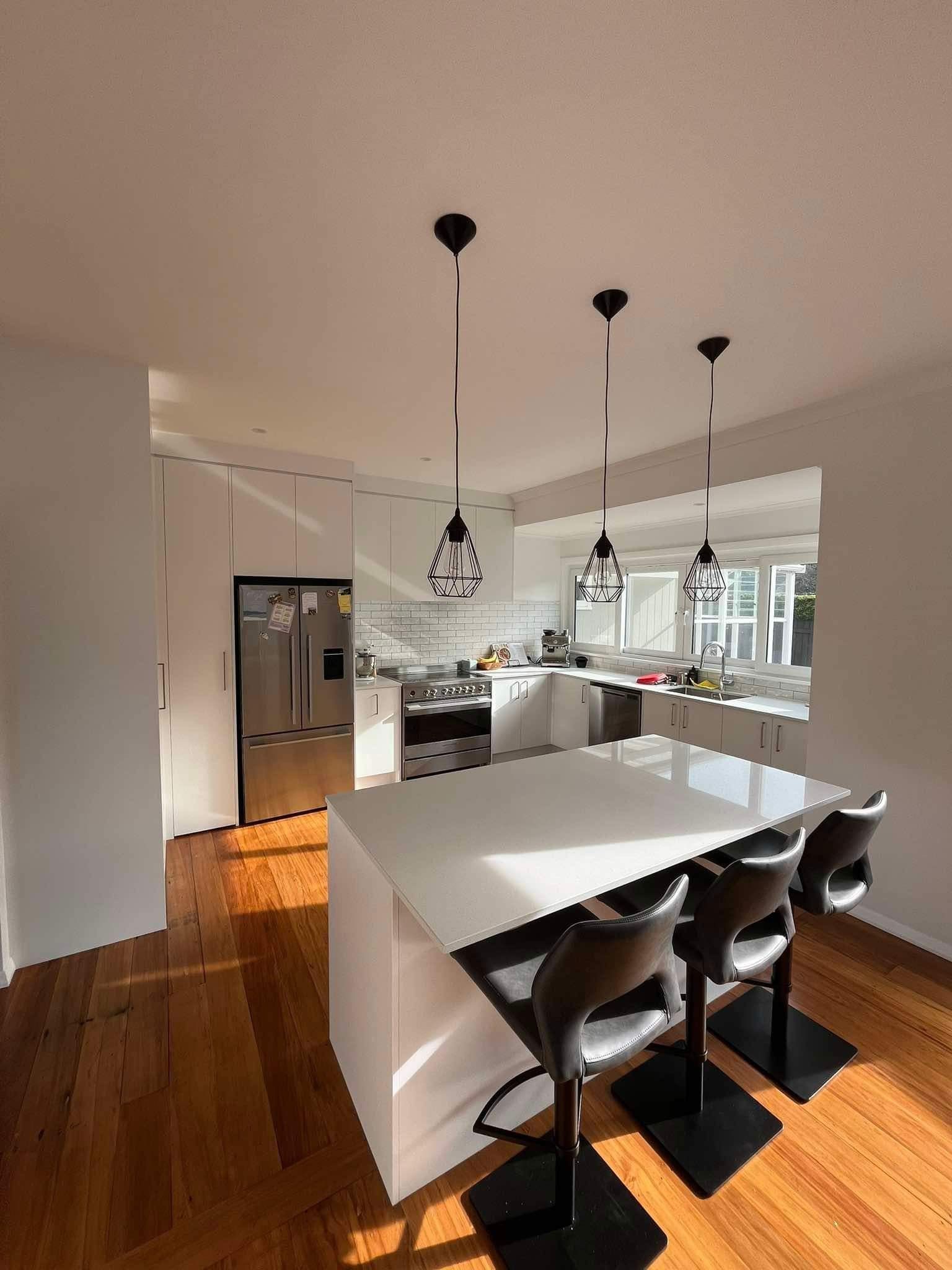 A kitchen with a large white table and chairs