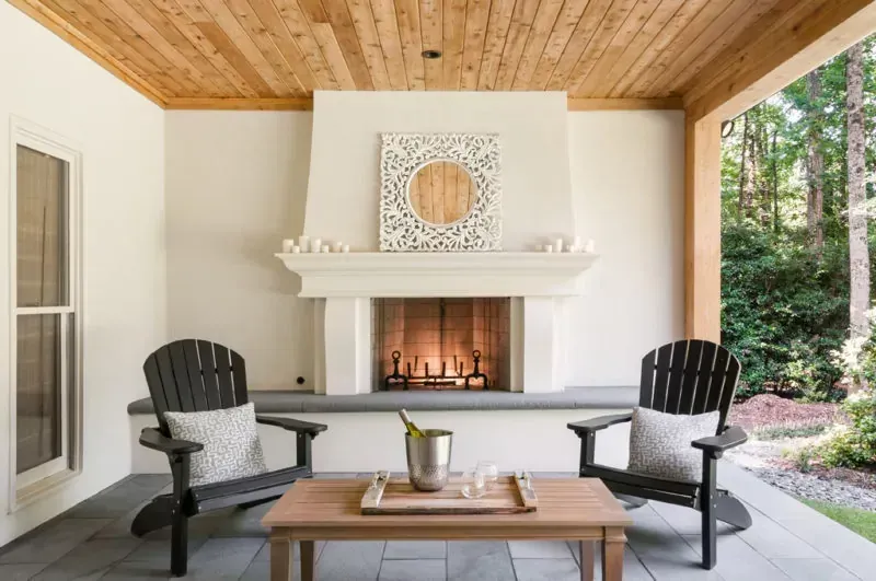 There is a fireplace on the patio with two chairs and a table.