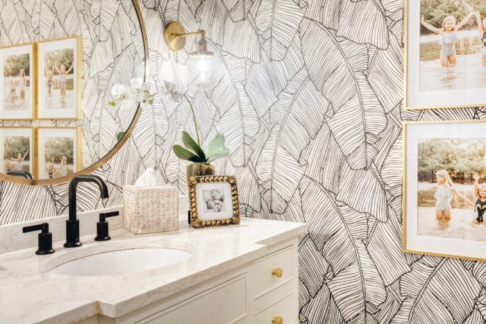 A bathroom with a sink , mirror , and pictures on the wall.