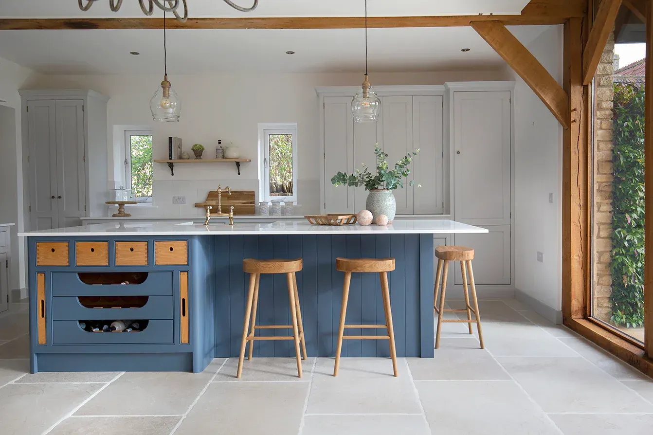 A kitchen with a blue island and wooden stools.