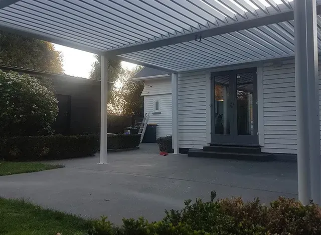 A white house with a patio and a pergola over it.