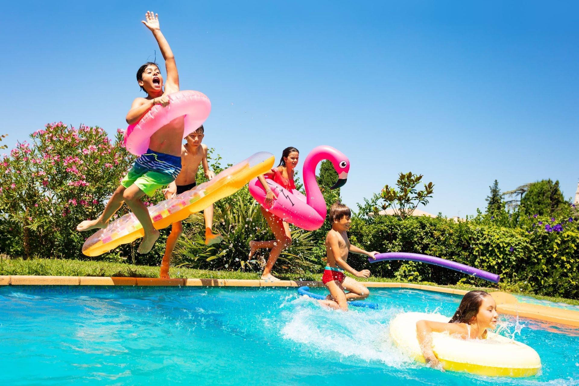 A group of children are jumping into a swimming pool.