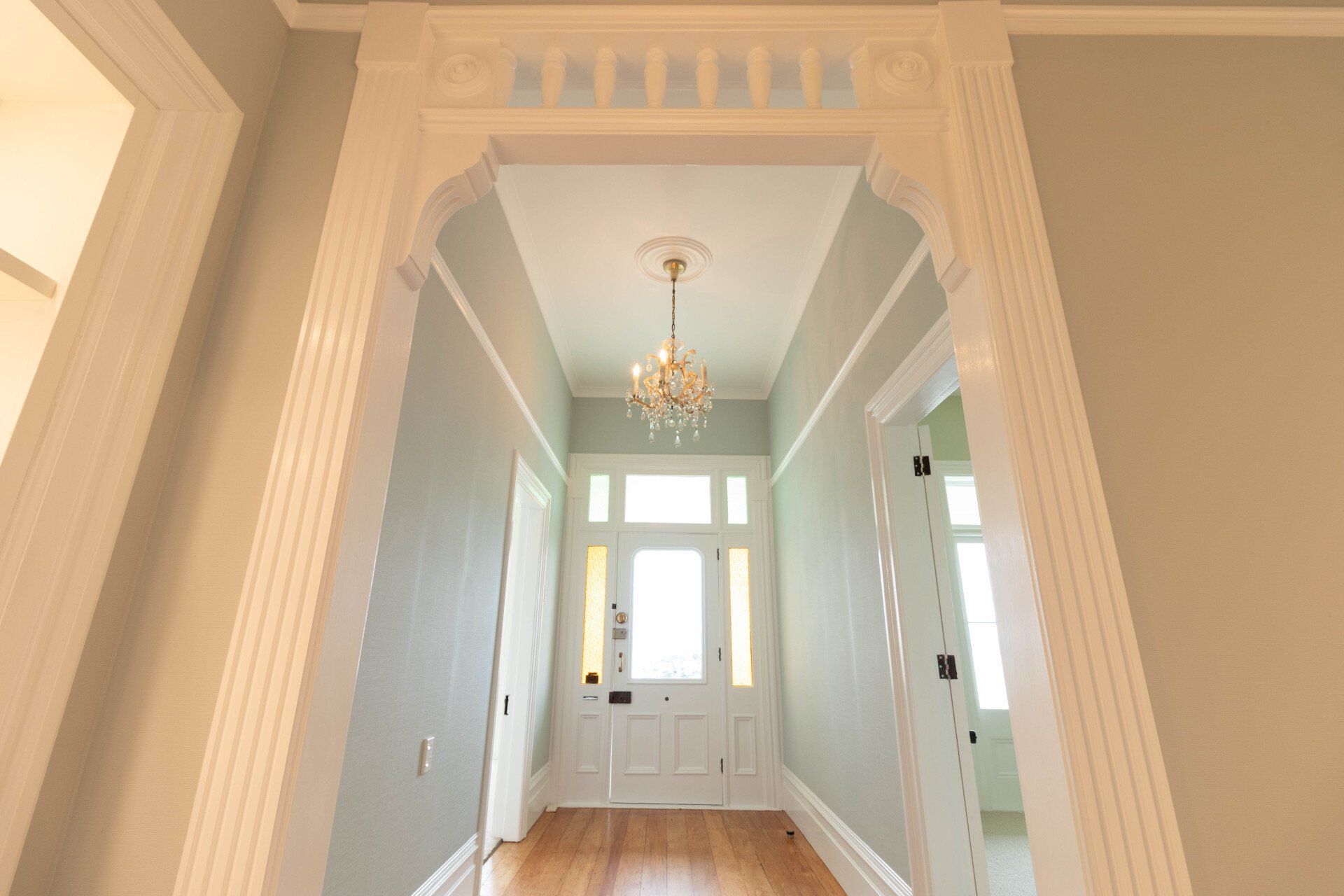 A hallway in a house with a chandelier hanging from the ceiling.