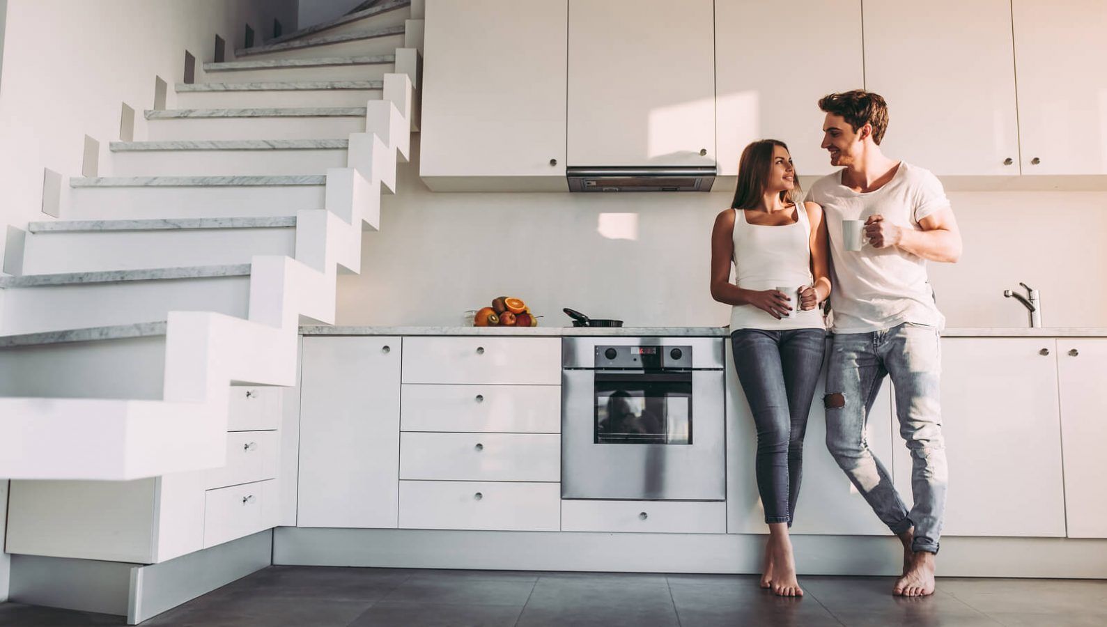 A man and a woman are standing in a kitchen looking at each other.