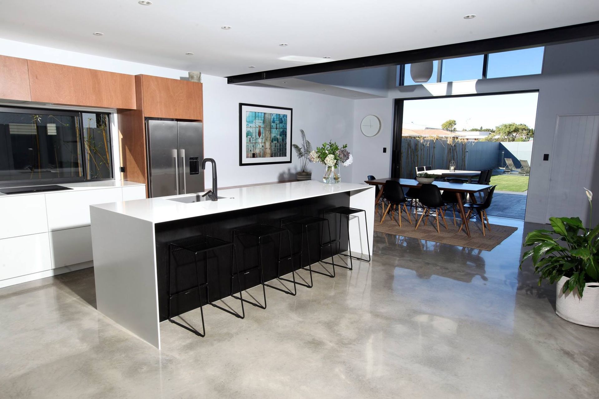 Modern kitchen with black island, stainless appliances, and open view to patio dining area
