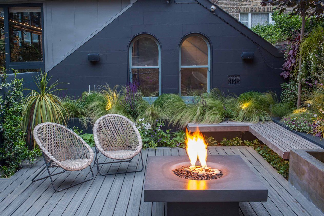 There is a fire pit on the deck with chairs around it.