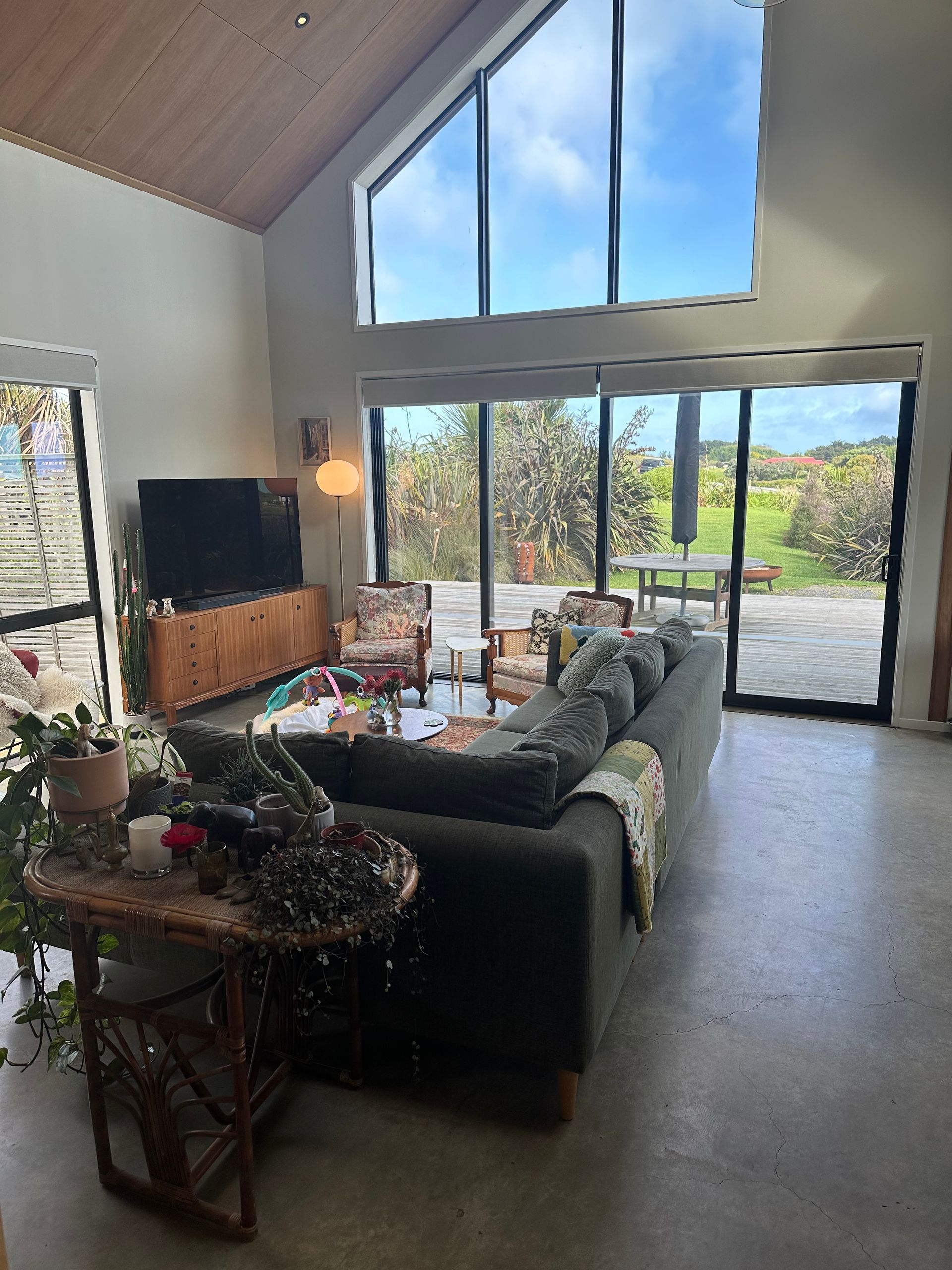 A living room with a couch , table , television and large windows.