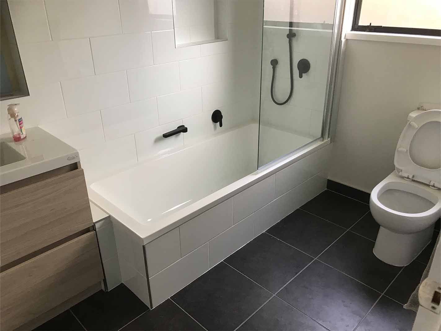 A bathroom with a toilet , sink and bathtub.