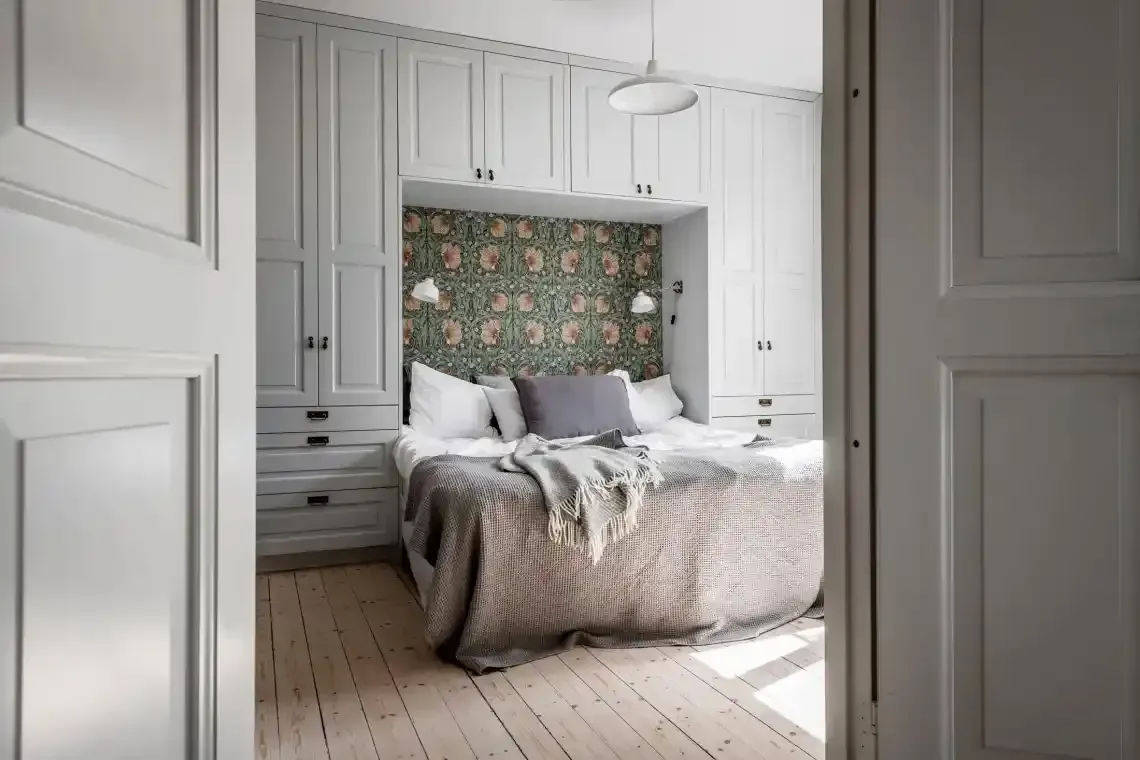 A bedroom with a bed and lots of cabinets and drawers.