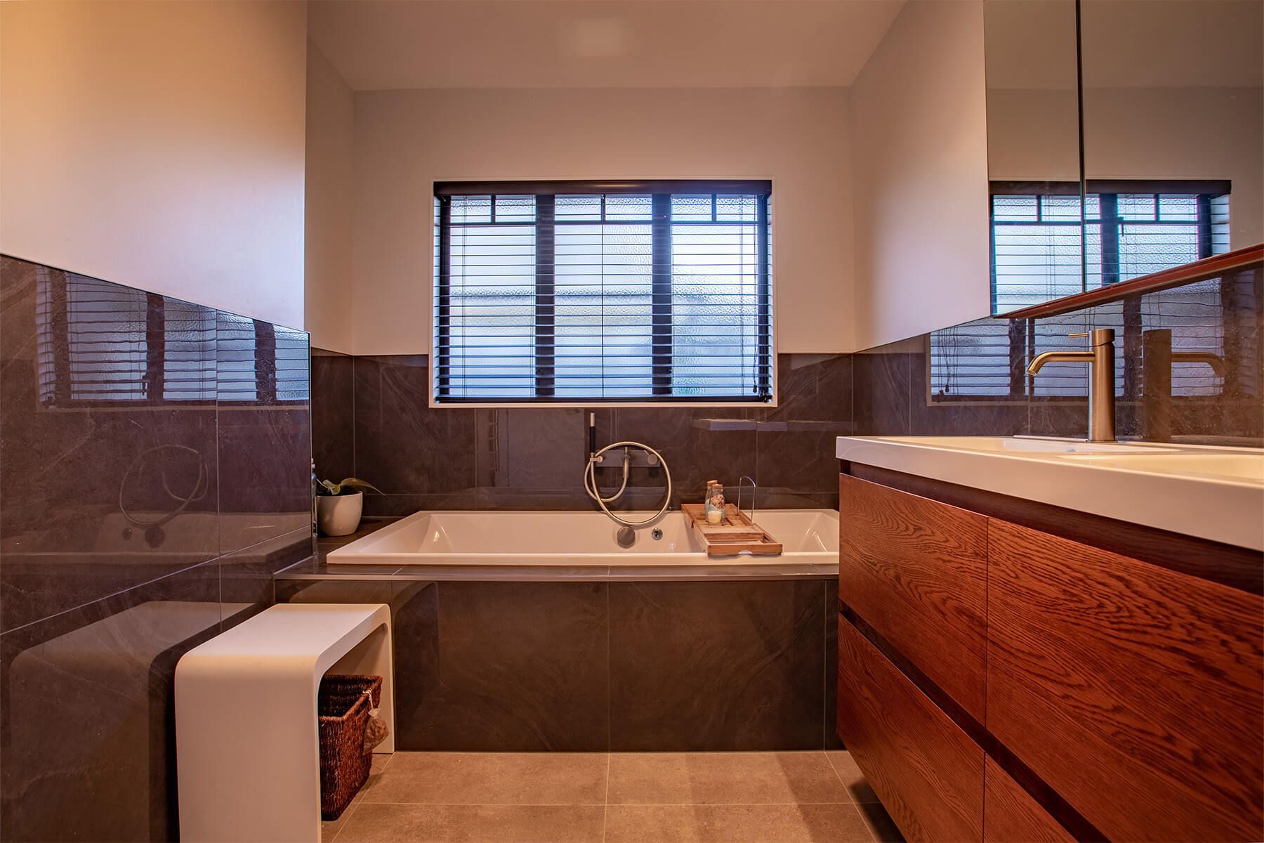 A bathroom with a tub , sink , mirror and window.