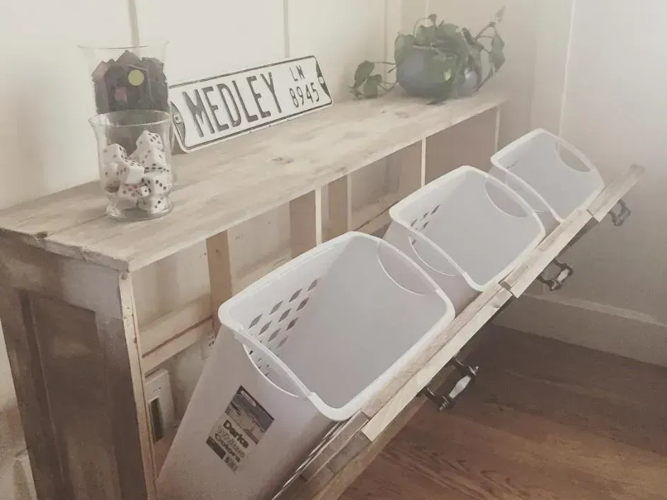 Three laundry baskets are pulled out of a wooden shelf.
