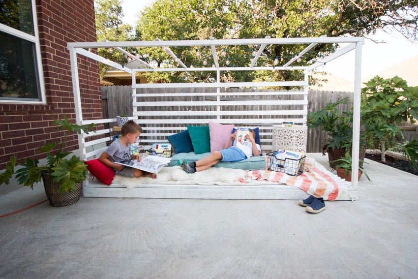 Two children are sitting on a couch on a patio.