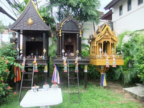 A group of small temples are sitting on top of a lush green field.