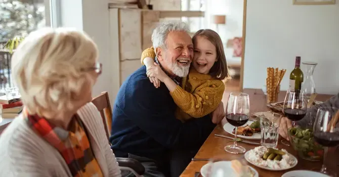 A little girl is hugging an older man at a dinner table.