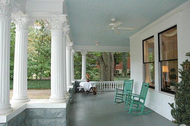 A porch with two blue rocking chairs and a ceiling fan