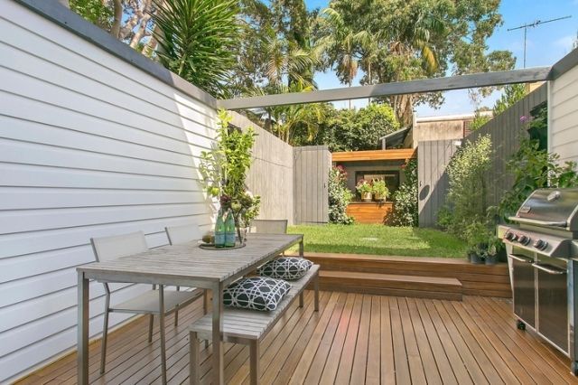 A wooden deck with a table and chairs and a grill.
