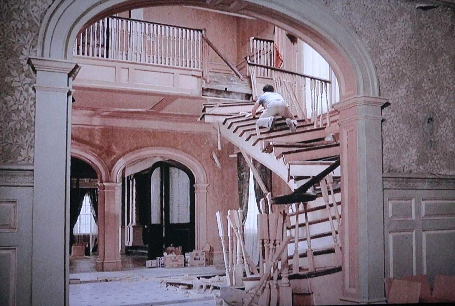 A man is standing on a set of stairs in a house.