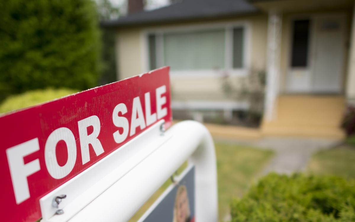 A for sale sign is in front of a house.
