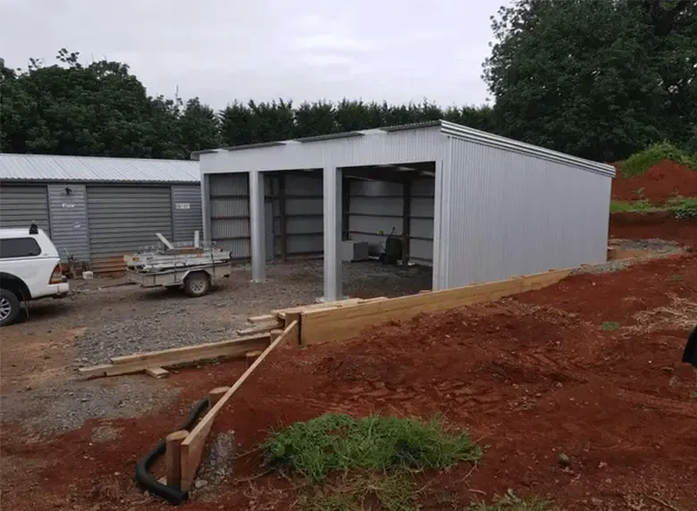 A white truck is parked in front of a garage under construction.