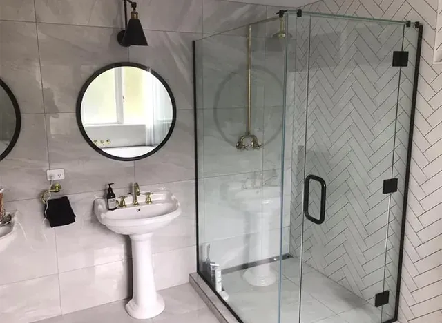 A bathroom with a sink , mirrors , and a walk in shower.
