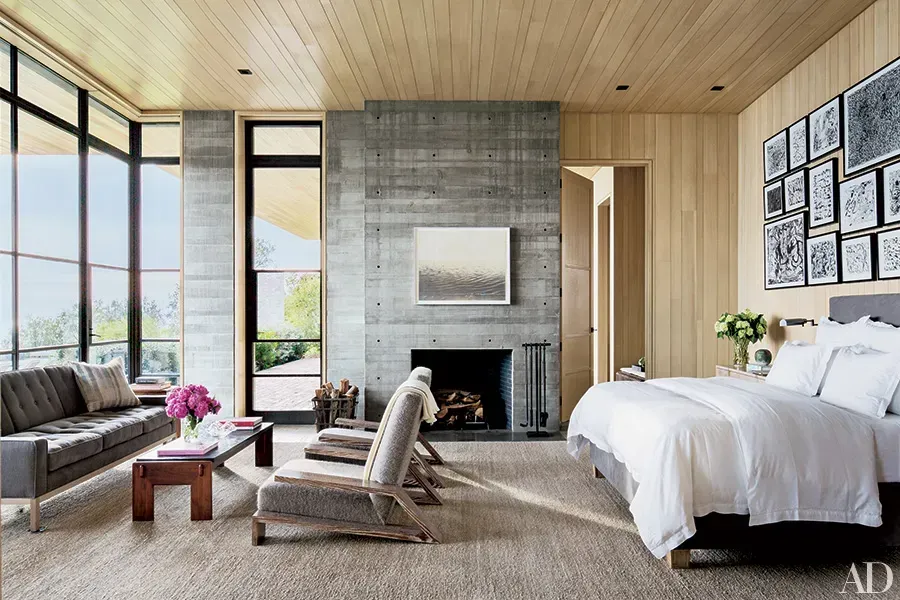 A bedroom with a couch , chairs , and a fireplace.