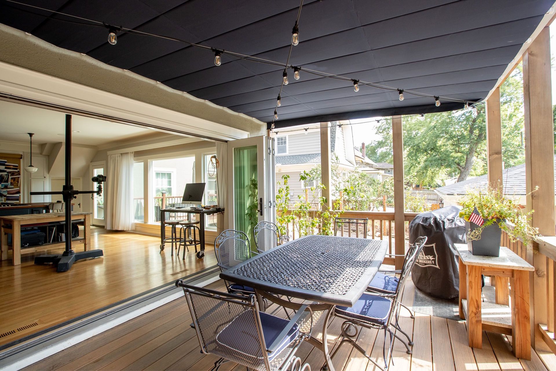 There is a table and chairs on the porch of a house.