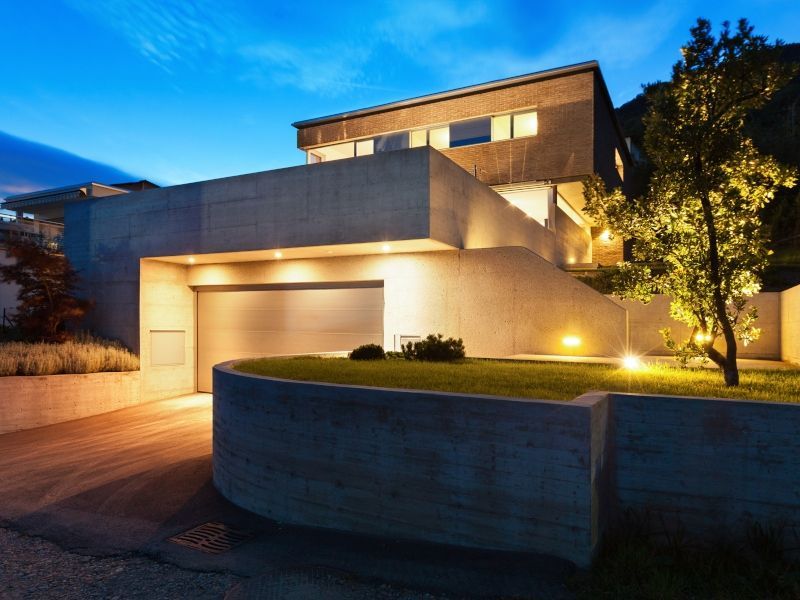 The house is lit up at night and has a large garage.