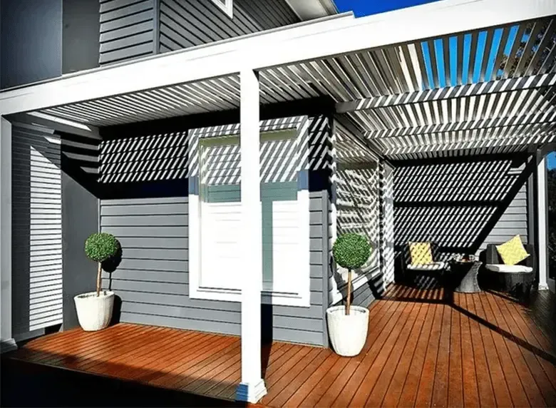 A porch with a pergola and a wooden deck in front of a house.