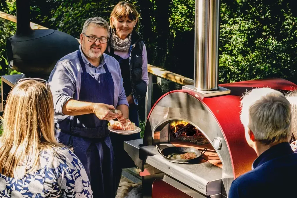 A group of people are standing around a pizza oven.