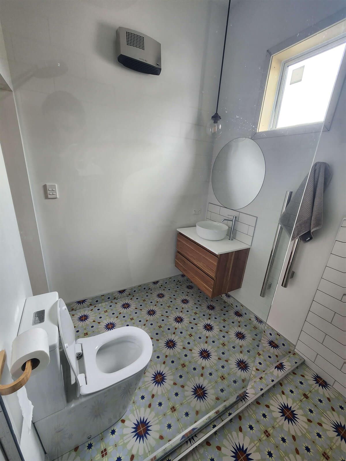 A bathroom with a toilet , sink and mirror.