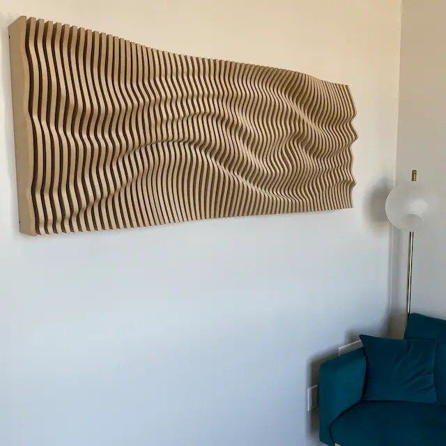 A large wooden sculpture is hanging on a wall next to a blue couch.